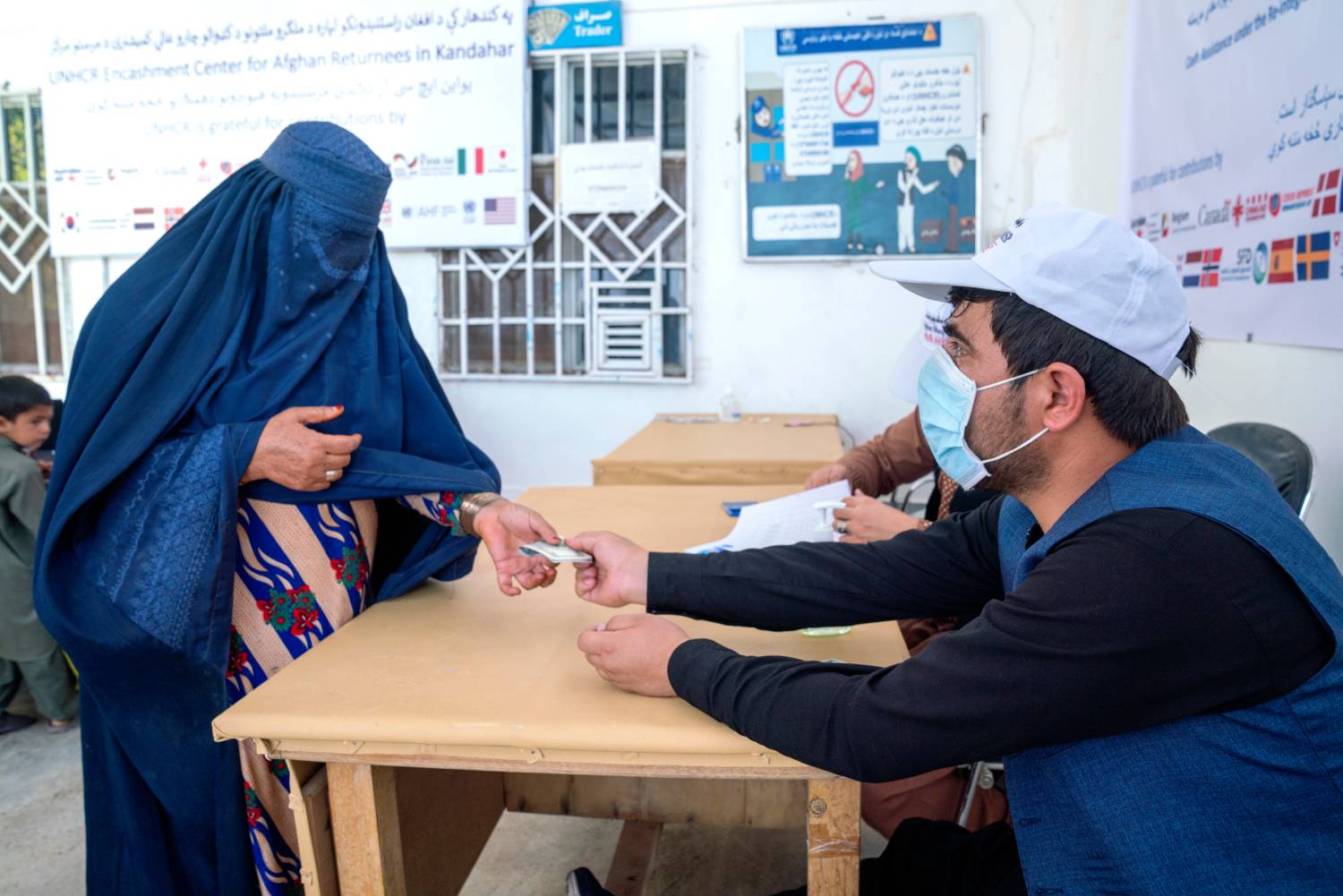 An Afghan woman collects cash assistance