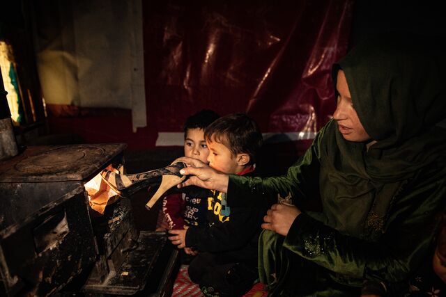A family uses plastic shoes to light their stove to keep warm. 
