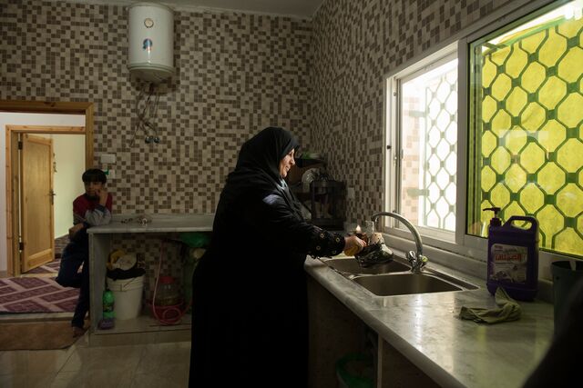 Nahlah washes dishes at home in her apartment in Mafraq, Jordan.