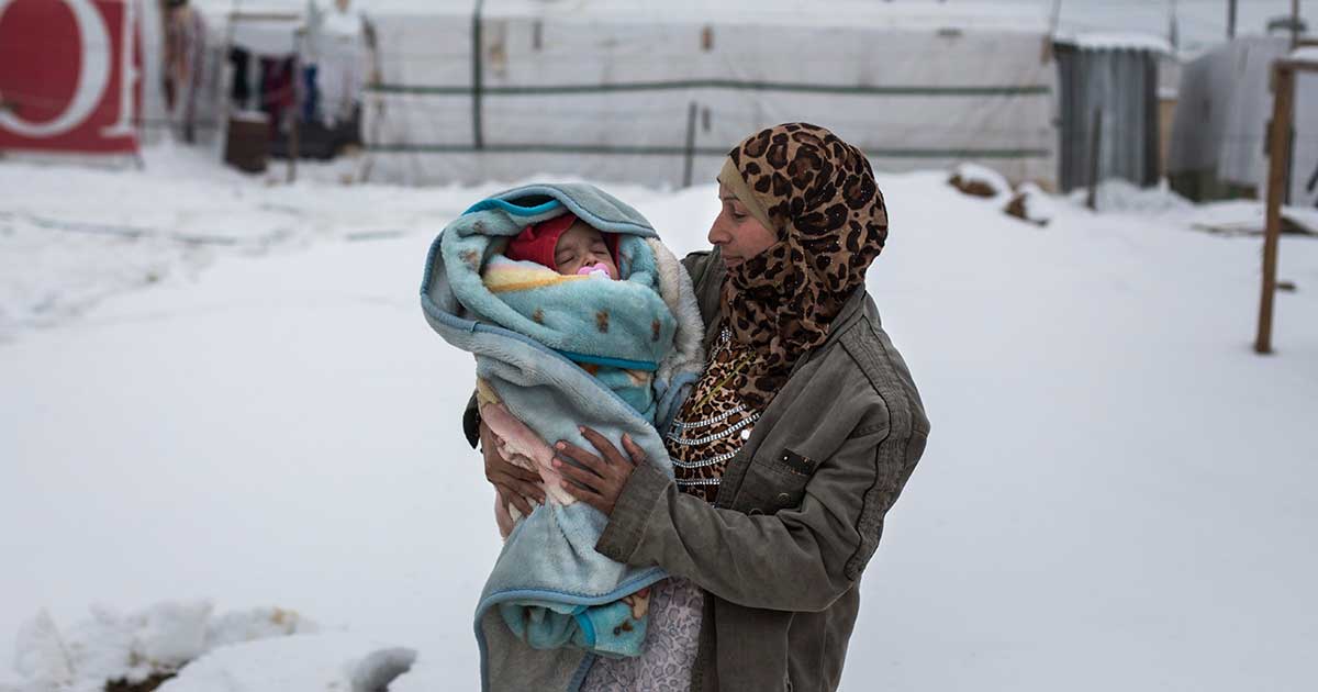4 month old baby Yousef is held by his mother, Fatima in Dilhamye tented settlement in Bekaa Valley, Lebanon