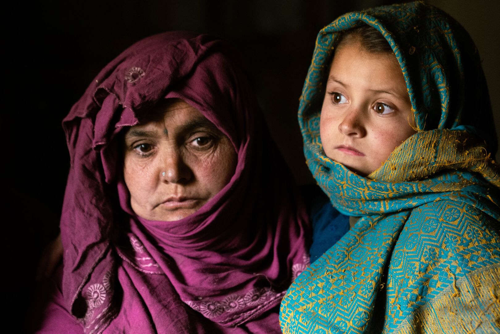 Afghan widow and mother of six, Hakima stands with her child inside their home in Bamyan, Afghanistan.