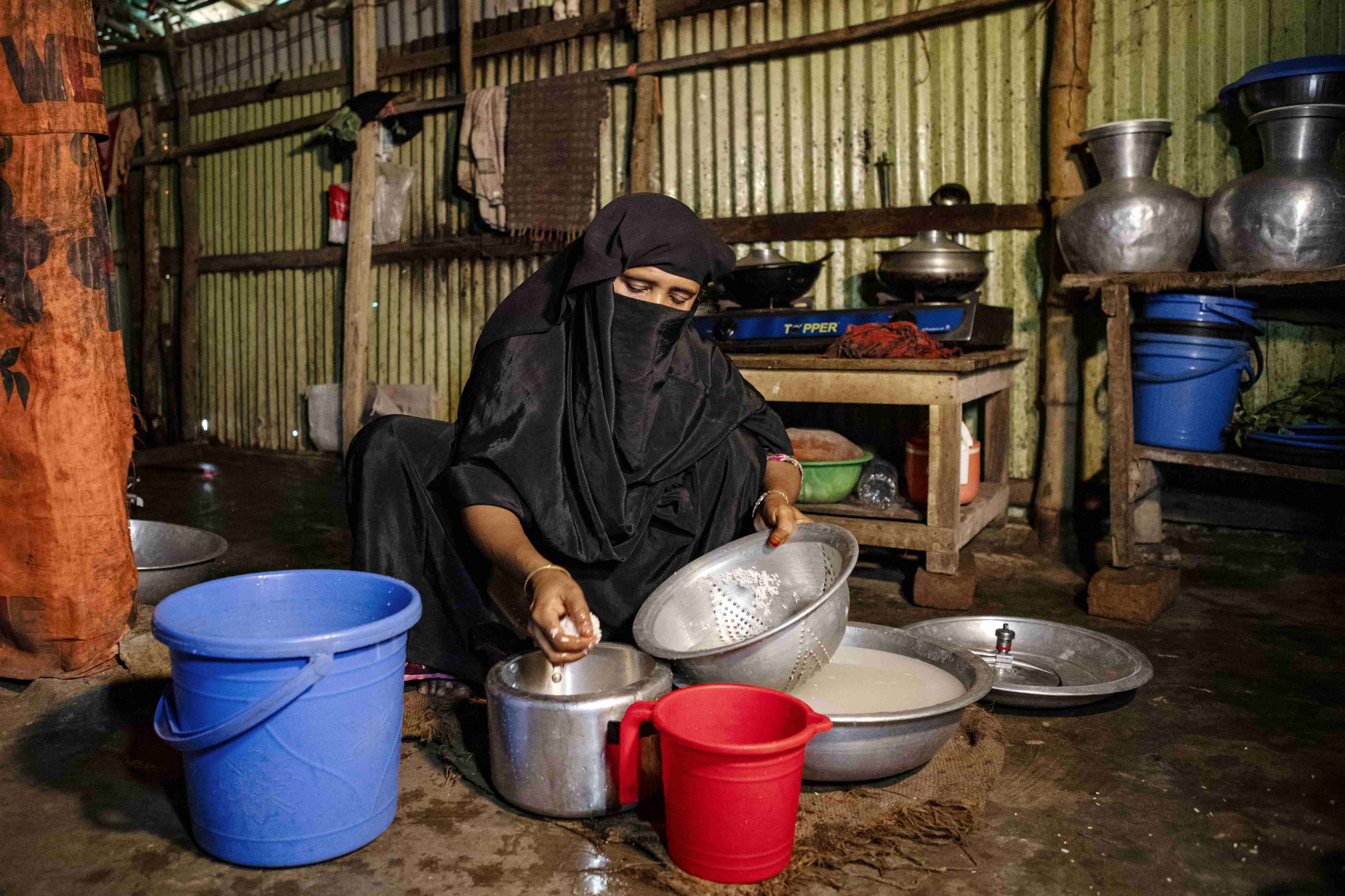 A Rohingya woman prepares lunch using a fuel-efficient pot provided by UNHCR