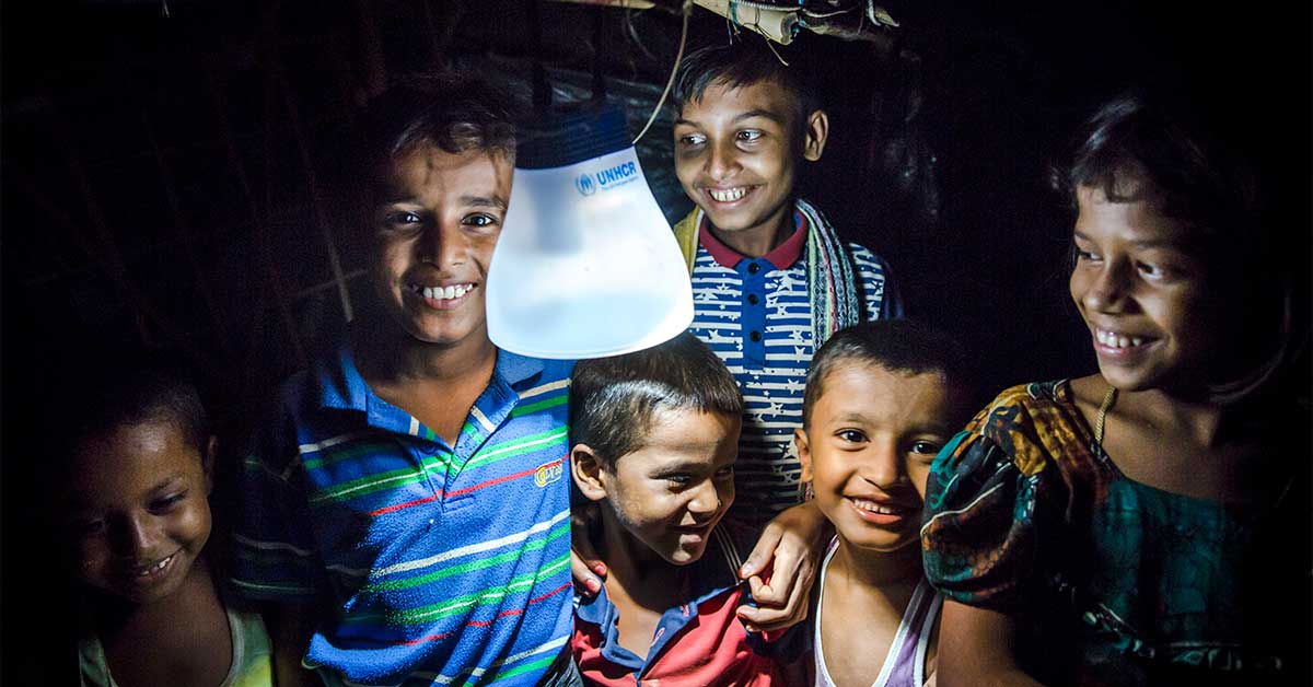 Young children in Bangladesh gather round a solar lamp at night | Ramadan charity gifts