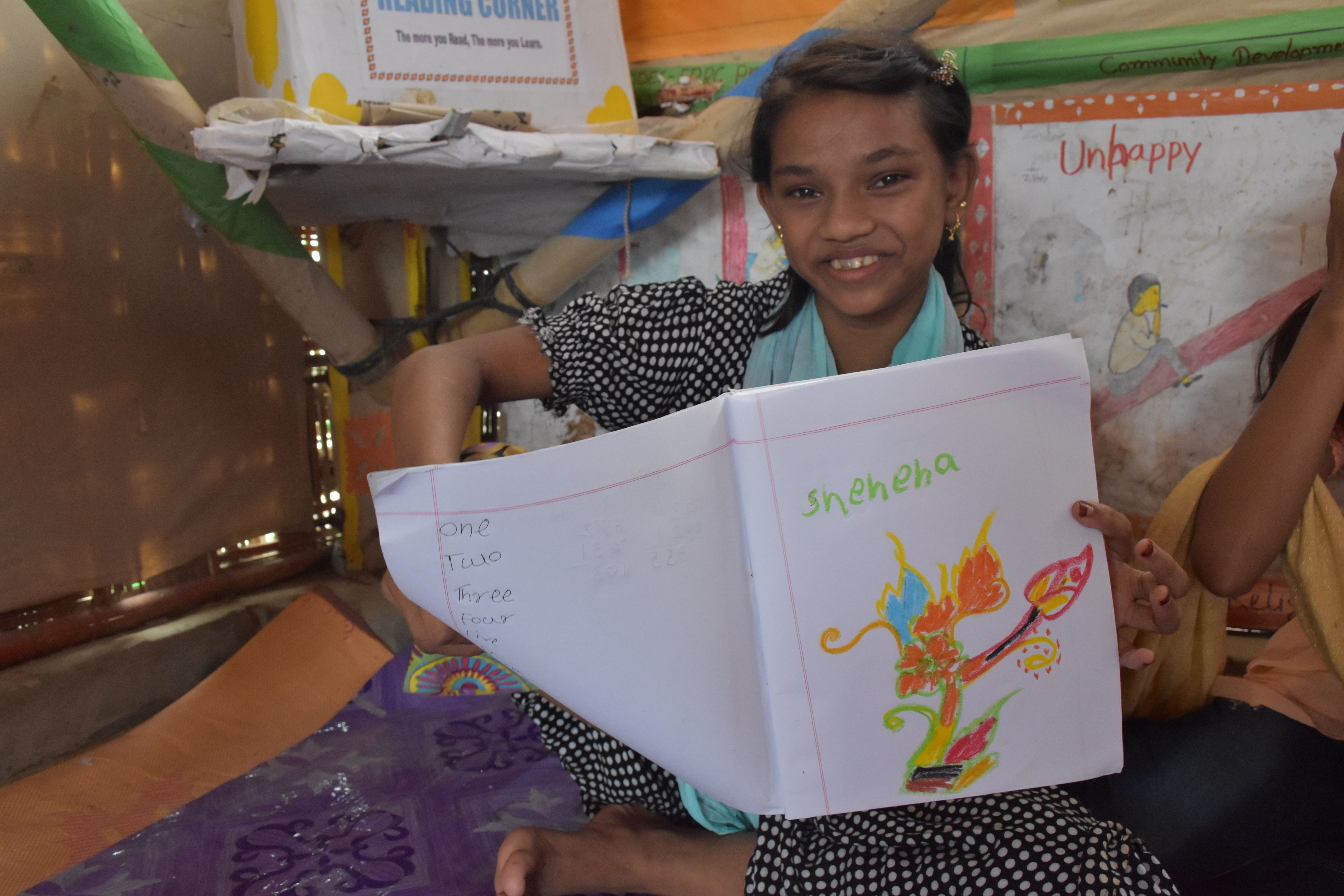 Shehana, Rohingya refugee holds artwork. She studies at the Diamond Adolescent Club set up by UNHCR partner.