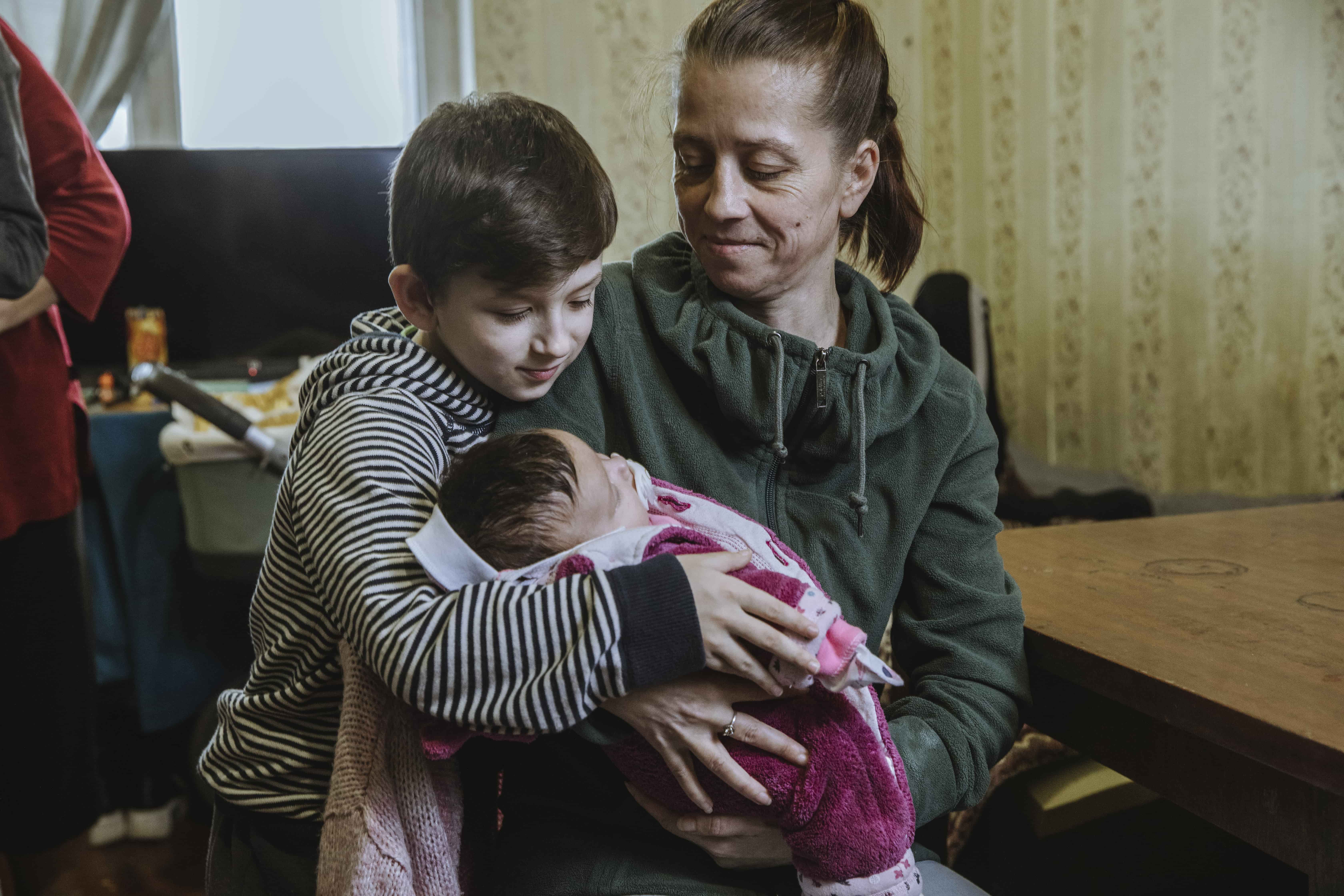 Katia holds her newborn baby, Malinka, while her son Oleksi, 8, looks on.