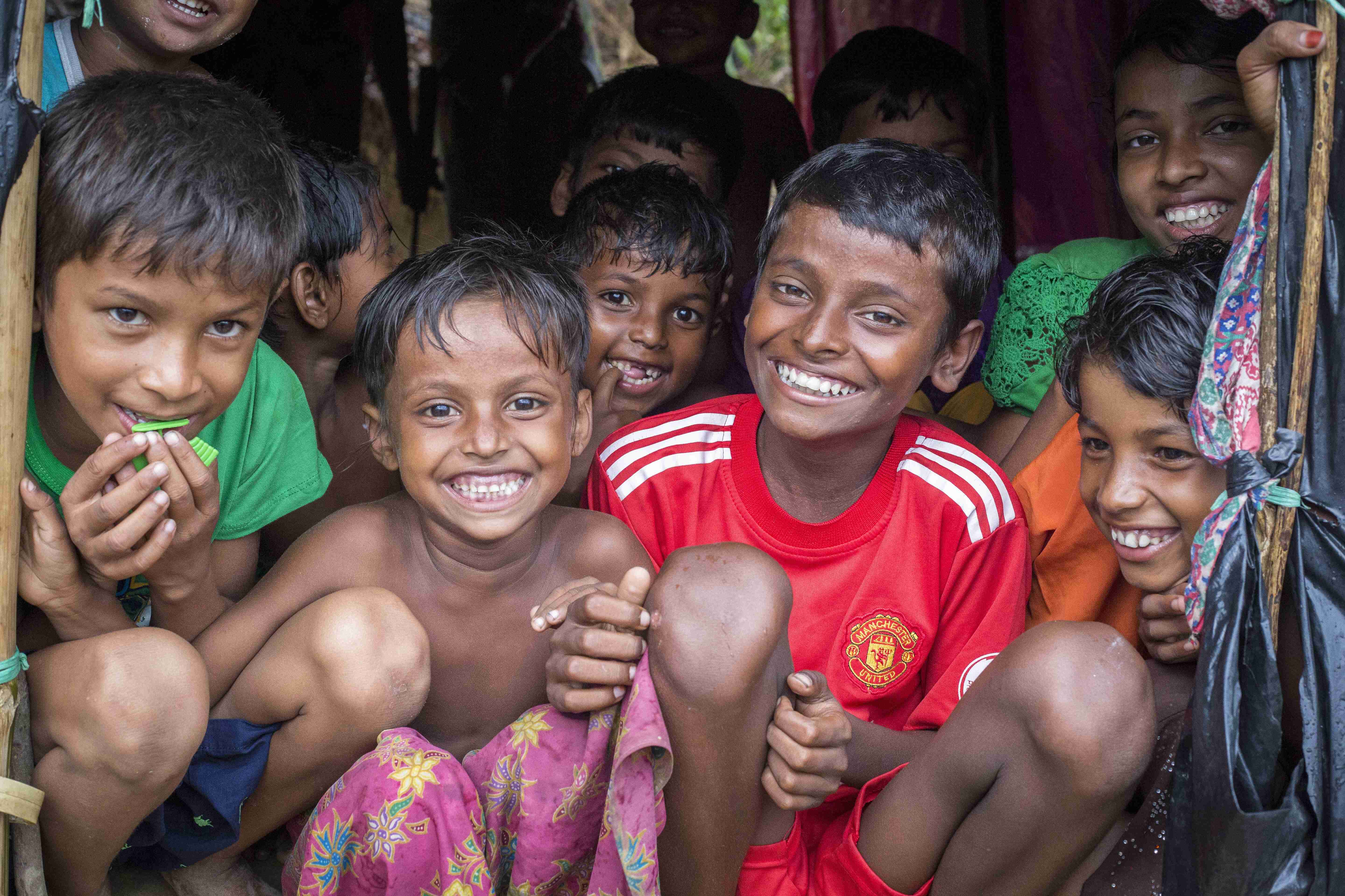 Rohingya children shelter from the heavy monsoon rains at Kutupalong refugee camp in Cox's Bazar, Bangladesh. ; As an estimated 500,000 Rohingya sought safety in Bangladesh between late-August and October 2017, UNHCR began work on an extension site next to the long-established Kutupalong refugee camp in Cox’s Bazar.